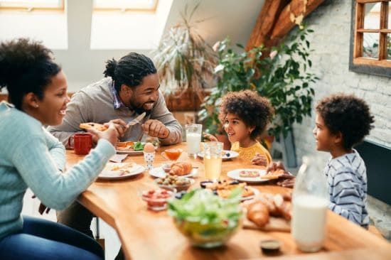 Family sharing a meal at a dining table in a well-lit interior.
